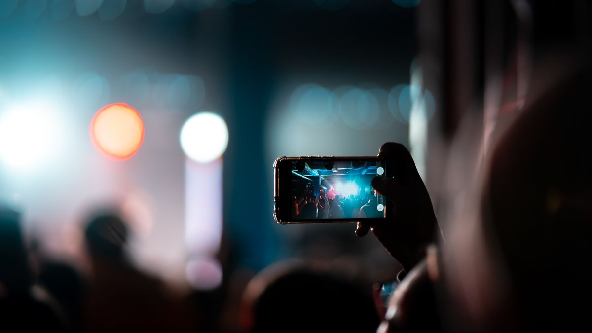 Smartphone screen recording video at live concert with stage lights
